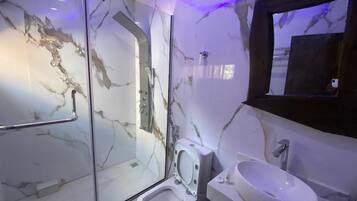 Un baño moderno con ducha de vidrio, un bidé y un lavamanos.