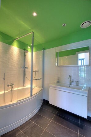 Een moderne badkamer met een douchecabine van glas, een vrijstaand bad en een wastafel met spiegel.