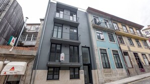 A multi-story building with balconies, a visible door, and a sign indicating a business on the ground floor. - Modern Flat Near Trindade by LovelyStay (Porto)