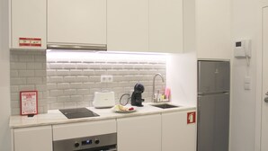 A modern kitchen with white cabinets, a stainless steel refrigerator, a built-in oven, and a sink with a faucet. - Modern Flat Near Trindade by LovelyStay (Porto)