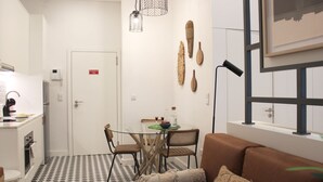 A compact living space with a kitchenette, a dining area with a glass table, and a sofa. - Modern Flat Near Trindade by LovelyStay (Porto)