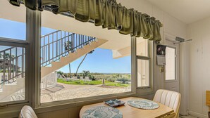 A dining area with a view of a staircase and outdoor patio. - Directly on the Gulf - Unit  2  - 1 Bedroom - Ground Floor - Sleeps up to 4 (Venice)