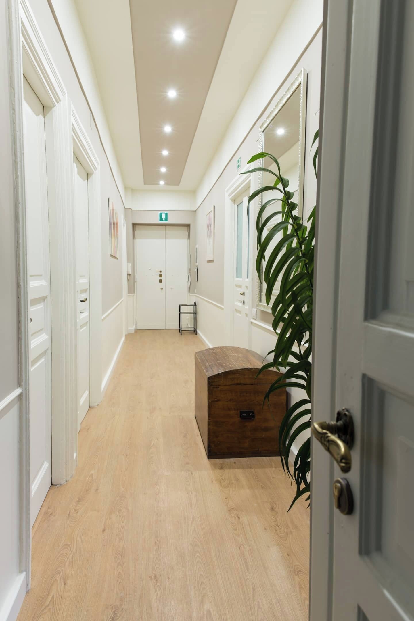 Een hal met houten vloer, witte muren en een houten dressoir.