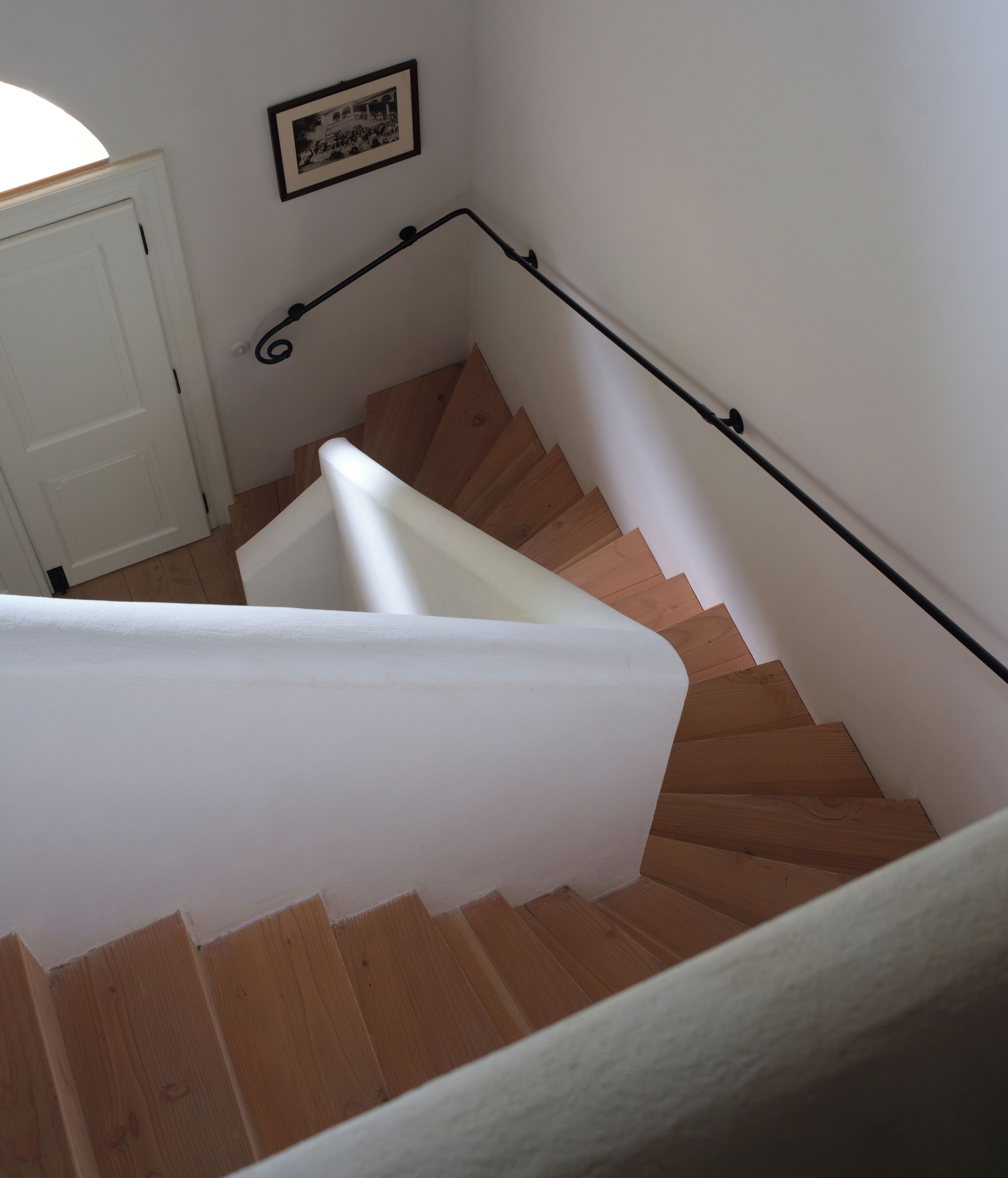 A wooden staircase with a white handrail and a white door at the top.