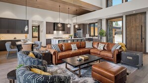 A spacious living room with a leather sectional sofa, a coffee table, and a dining area with a table and chairs. - Luxury Tahoe Estate | AC & Hot Tub | EV Charger| Golf Access, Near Lake & Trails (Truckee)