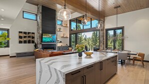 A modern kitchen with a large island, wooden cabinets, and pendant lighting. - Luxury Tahoe Estate | AC & Hot Tub | EV Charger| Golf Access, Near Lake & Trails (Truckee)