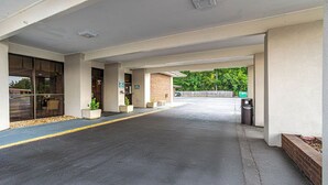 A covered parking area with a clear path leading to a building entrance, a trash bin, and a small planter with a plant. - Northgate Inn by Townhouse Hattiesburg I-59 (Hattiesburg)
