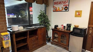 A small kitchenette with a refrigerator, microwave, coffee maker, and a window with a view of the street. - Northgate Inn by Townhouse Hattiesburg I-59 (Hattiesburg)
