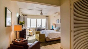 Une chambre d’hôtel avec un lit, un bureau, une chaise, une lampe et une fenêtre.