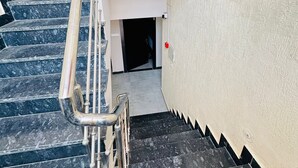 A staircase with black marble steps, metal handrails, and beige walls. - Hotel PSR Residency - near Temple & Ghat (Varanasi)