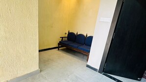 A hallway with a bench, a ceiling light, and a door. - Hotel PSR Residency - near Temple & Ghat (Varanasi)