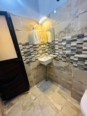 A small bathroom with a sink, mirror, and patterned tiles. - Hotel PSR Residency - near Temple & Ghat (Varanasi)