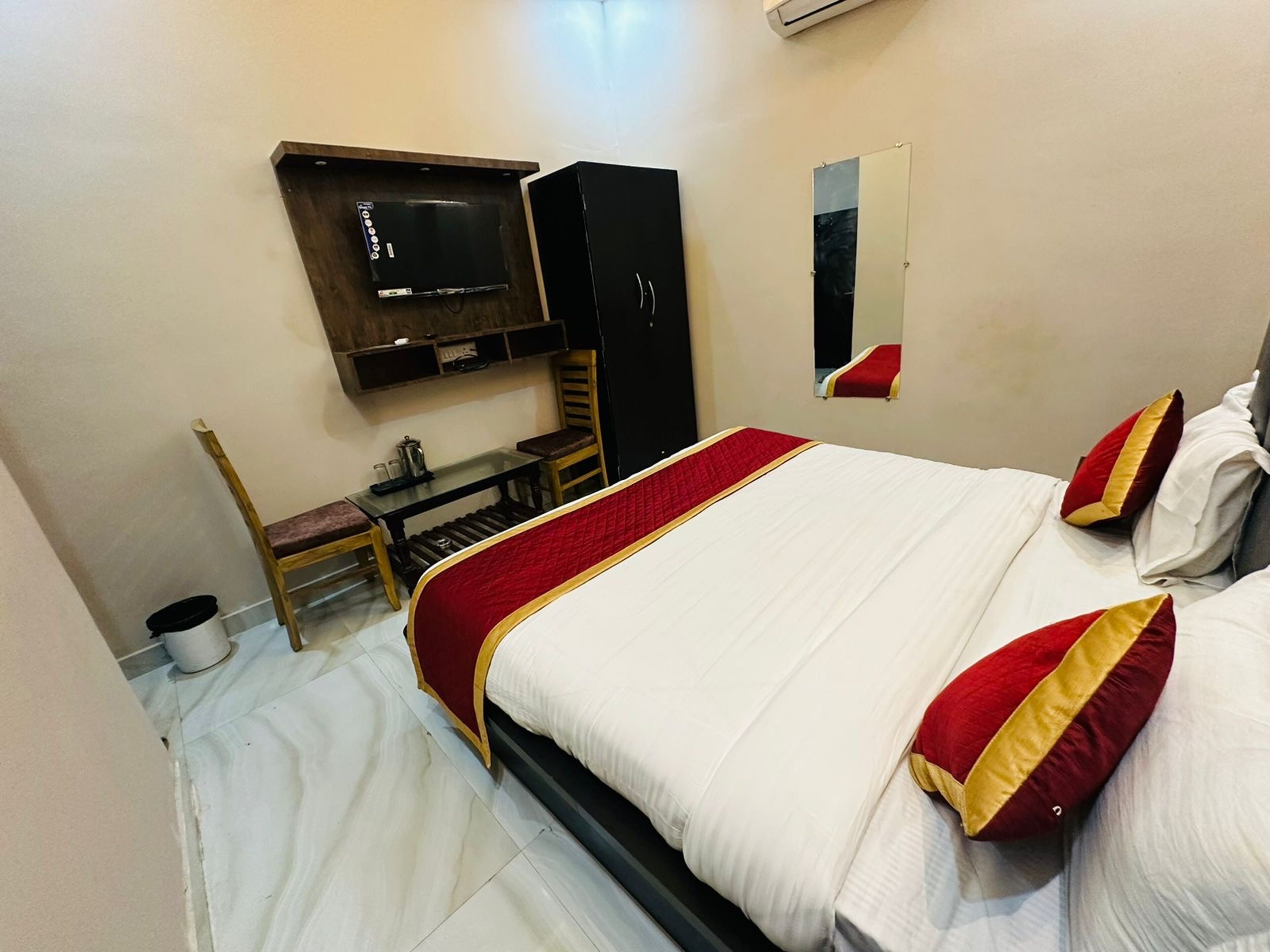 A hotel room with a bed, a desk, a chair, a television, and a mirror.