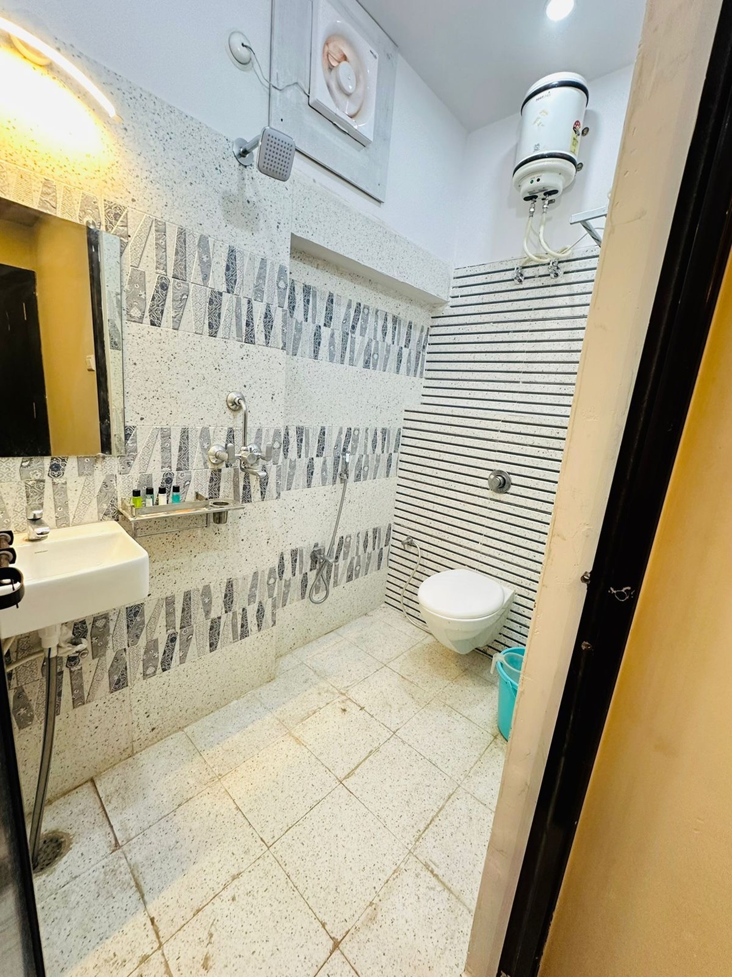 Une salle de bain avec un carrelage au sol, un lavabo, des toilettes et une douche dotée d’un panneau de commande.