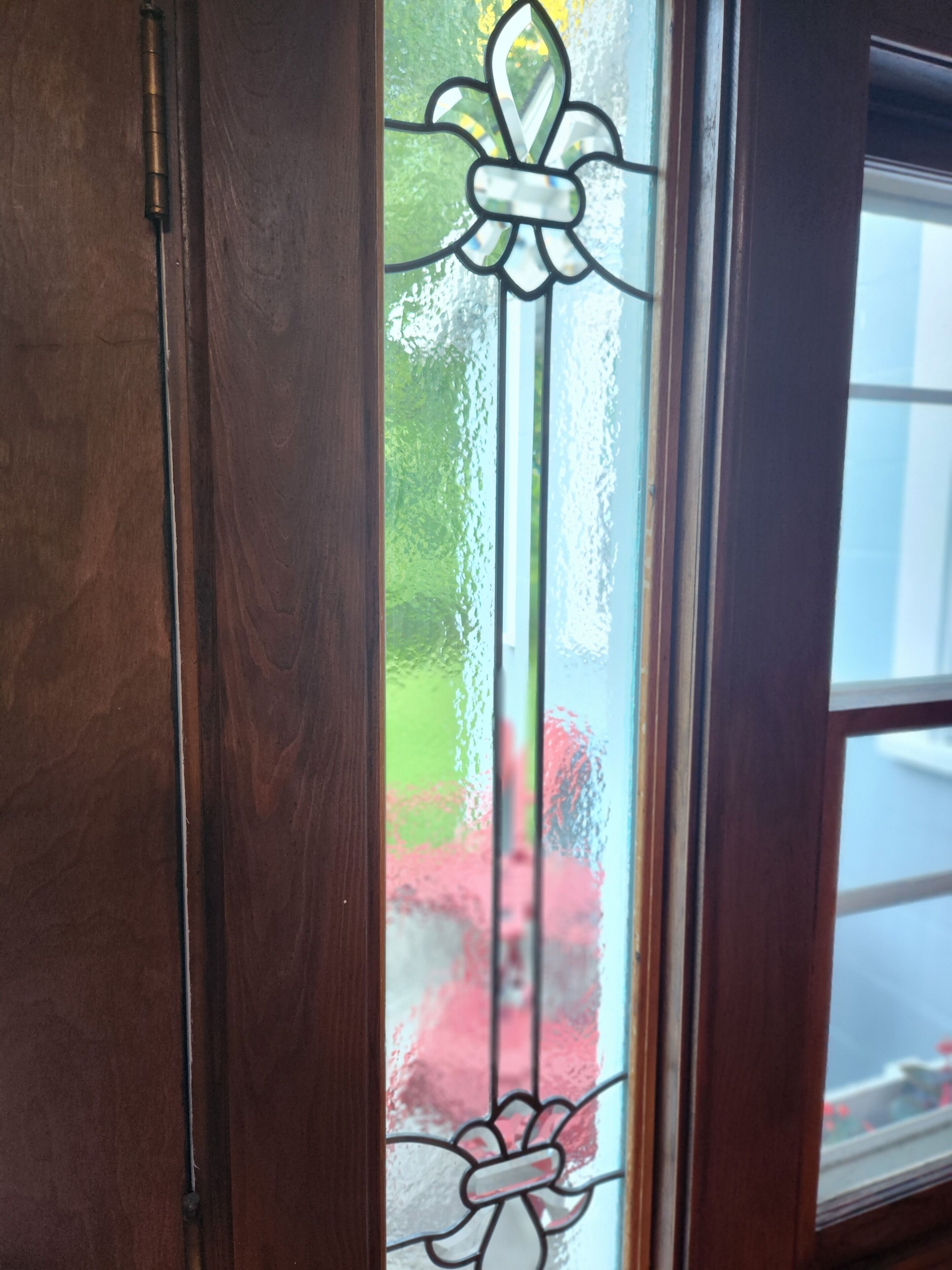 A wooden door with a glass window featuring a decorative glass design.
