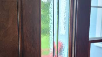 A wooden door with a glass window featuring a decorative glass design.
