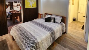 Een slaapkamer met een bed, houten vloer, dakraam, wandklok en een kaart aan de muur.