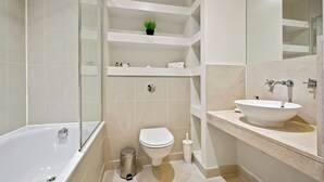 A modern bathroom with a bathtub, toilet, and sink. - 1 Bed South Quay Apartments Canary Wharf (London)