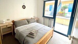 A bedroom with a bed, bedside tables, a window, and a view of the outside.