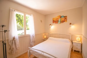 A bedroom with a bed, a window with curtains, a wall-mounted artwork, and bedside lamps. - Private 2-Bedroom Vacation Home in Canale-di-Verde (Canale-di-Verde)
