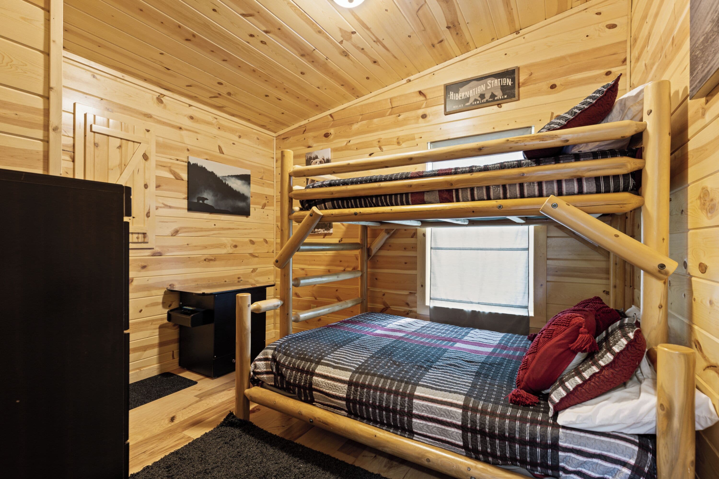 A bunk bed room with wooden walls, a window, and a sign that reads "Hibernation Station."
