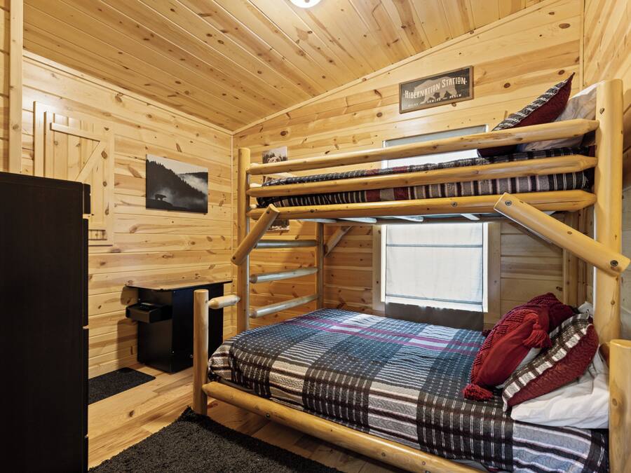 A bunk bed room with wooden walls, a window, and a sign that reads "Hibernation Station."