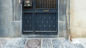 Eine schwarze Tür mit einem verzierten Metallgitter und einem kleinen Fenster darüber.