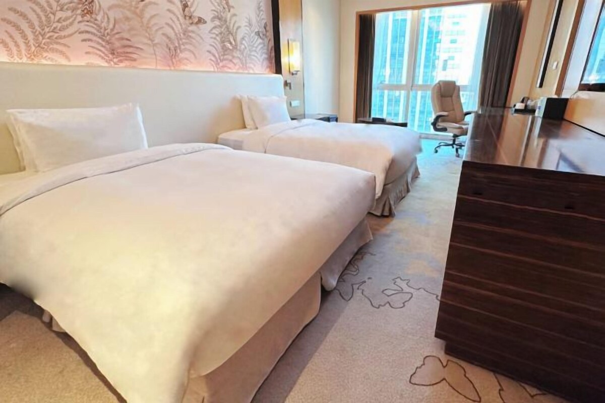 A hotel room with two beds, a desk, and a chair.