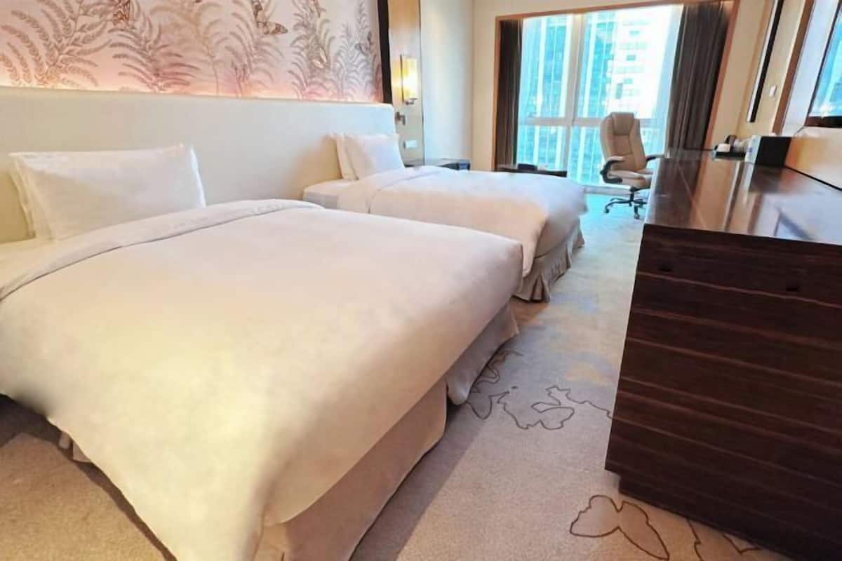 Ein Hotelzimmer mit zwei Betten, einem Schreibtisch und einem Stuhl.