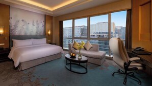 A hotel room with a large bed, a sofa, a desk, and a view of the city through large windows. - Yongkang World Trade International Hotel (Yongkang)