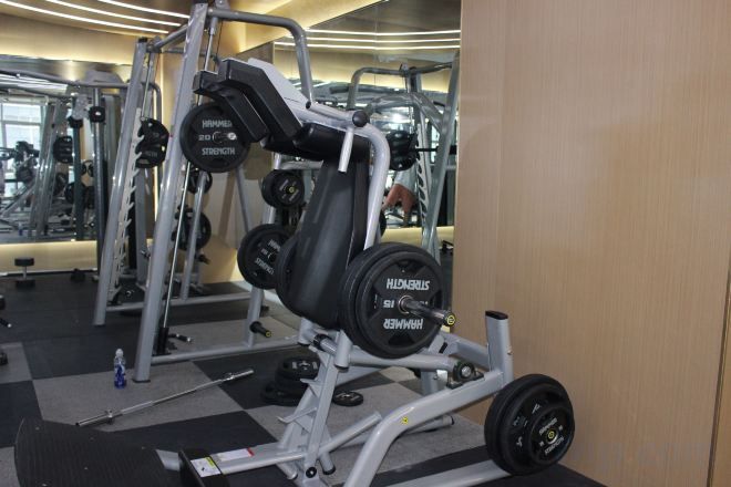 Ein Fitnessraum mit Gewichtstrainingsgeräten, darunter eine Smith-Maschine und Kurzhanteln.