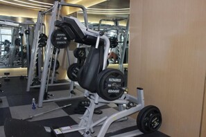 Een fitnessruimte met krachttrainingsapparatuur, waaronder een Smith-machine en haltergewichten.