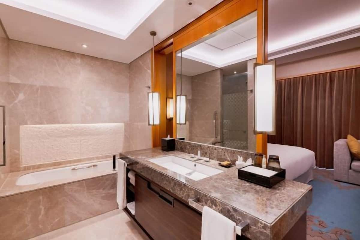 Ein modernes Badezimmer mit einem großen Spiegel, einer Badewanne und einem Waschbecken.