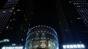 A hotel with a circular glass facade and illuminated signage. - Yongkang World Trade International Hotel (Yongkang)