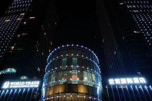 A hotel with a circular glass facade and illuminated signage. - Yongkang World Trade International Hotel (Yongkang)