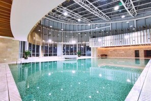 Une piscine intérieure dotée d’un plafond incurvé et d’un espace bar.