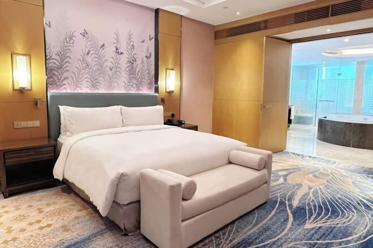 Ein Hotelzimmer mit einem großen Bett, einem Nachttisch, einer Wandlampe und einem durchgegangenen Tür erkennbaren Badezimmer.