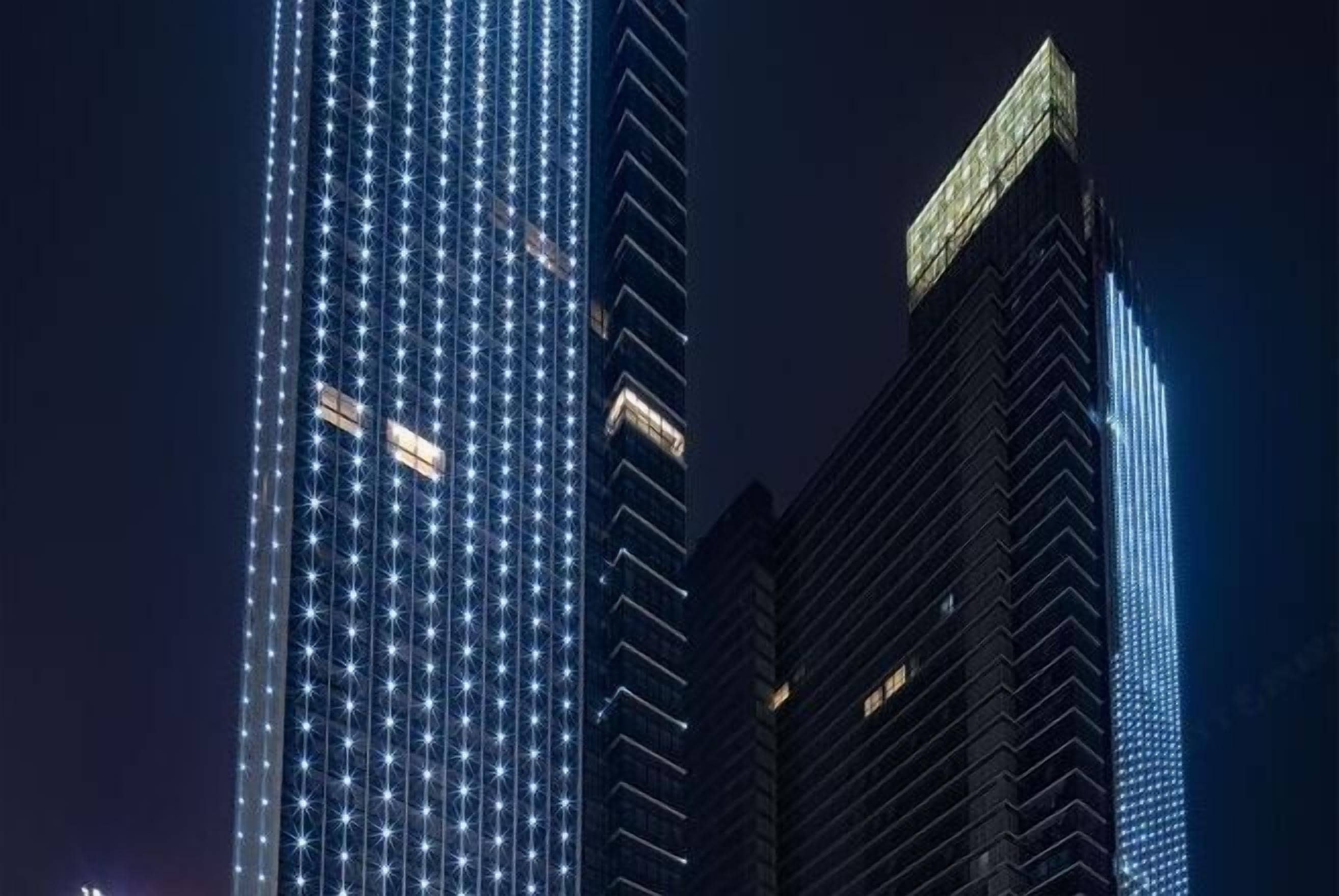 A night view of a cityscape with illuminated skyscrapers.