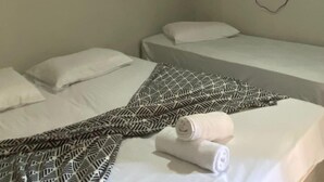 Et hotelværelse med to enkeltsenge, et fladskærms-tv ophængt på væggen og et mønstret tæppe på den ene seng.