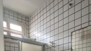 Et badeværelse med toilet, vask og bruseområde.