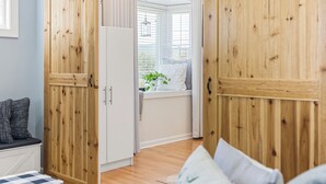 A room with wooden paneling, a white refrigerator, a window with blinds, and a view of greenery outside. - The Bell House - Contemporary Comfort Near Wards Road with a Luxurious Hot Tub! (Lynchburg)