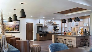 Uma cozinha moderna com ilha central, banquetas e iluminação pendente.