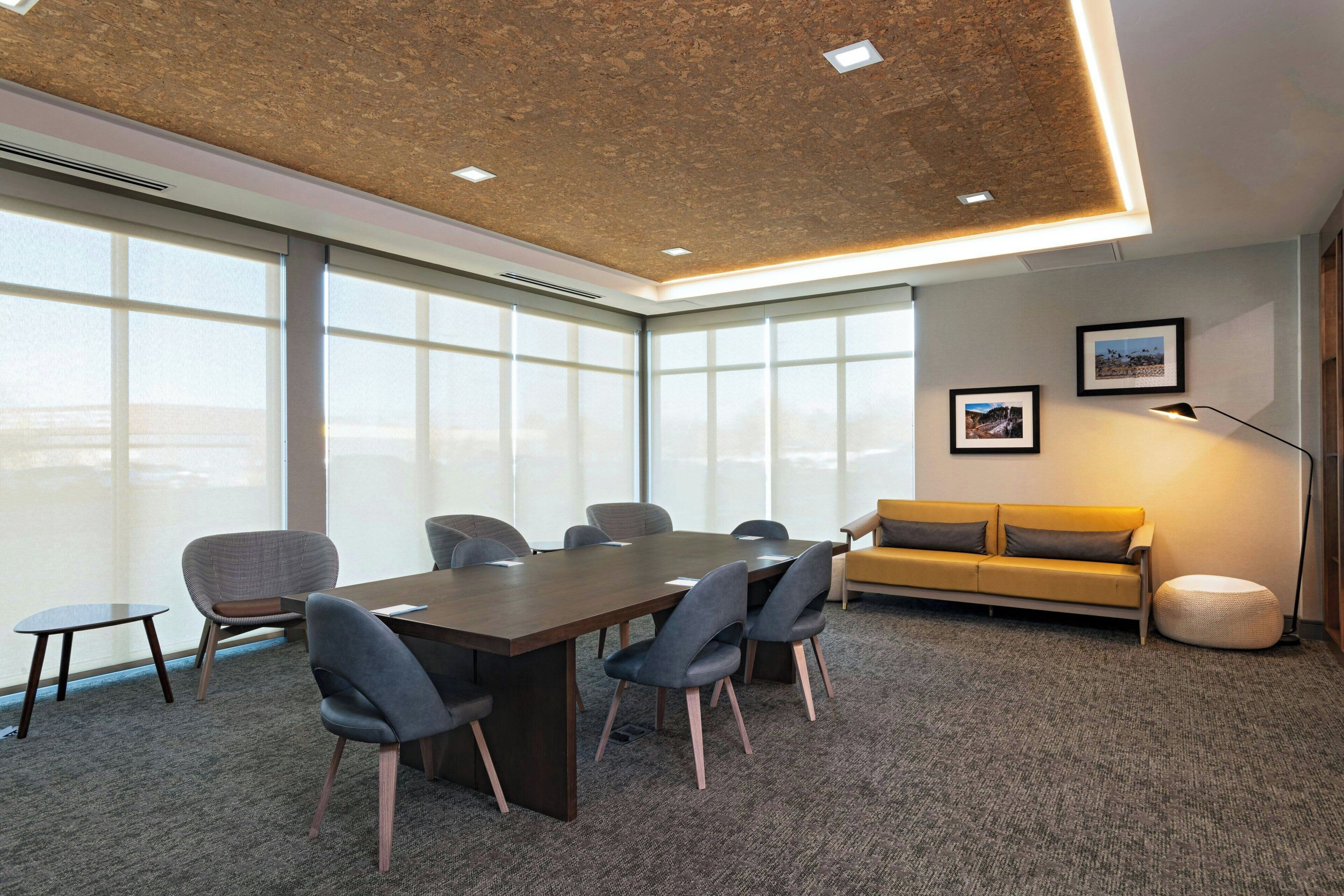 A conference room with a large table, chairs, a sofa, and a lamp.