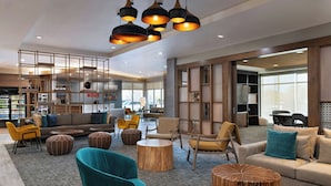 A modern hotel lobby with a sofa, chairs, a coffee table, and a wooden accent piece. - Towneplace Suites By Marriott Albuquerque Uptown (Albuquerque)