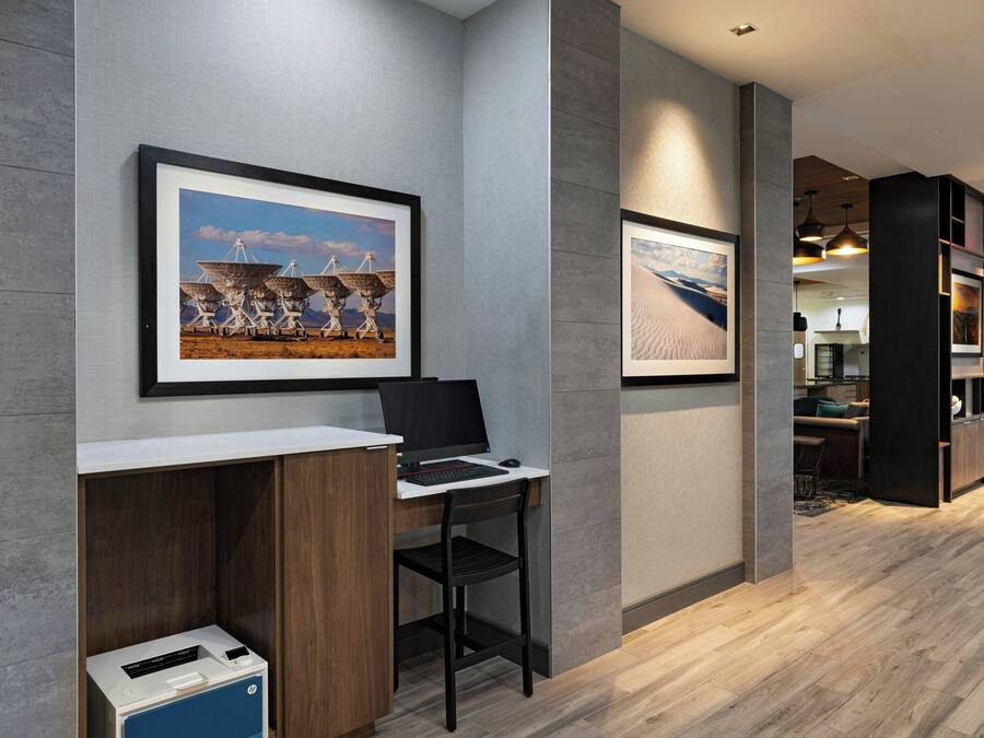 A modern office space with a desk, chair, and framed artwork on the wall.
