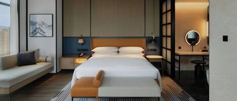 A modern hotel room with a large bed, a sofa, a desk, and a bathroom.