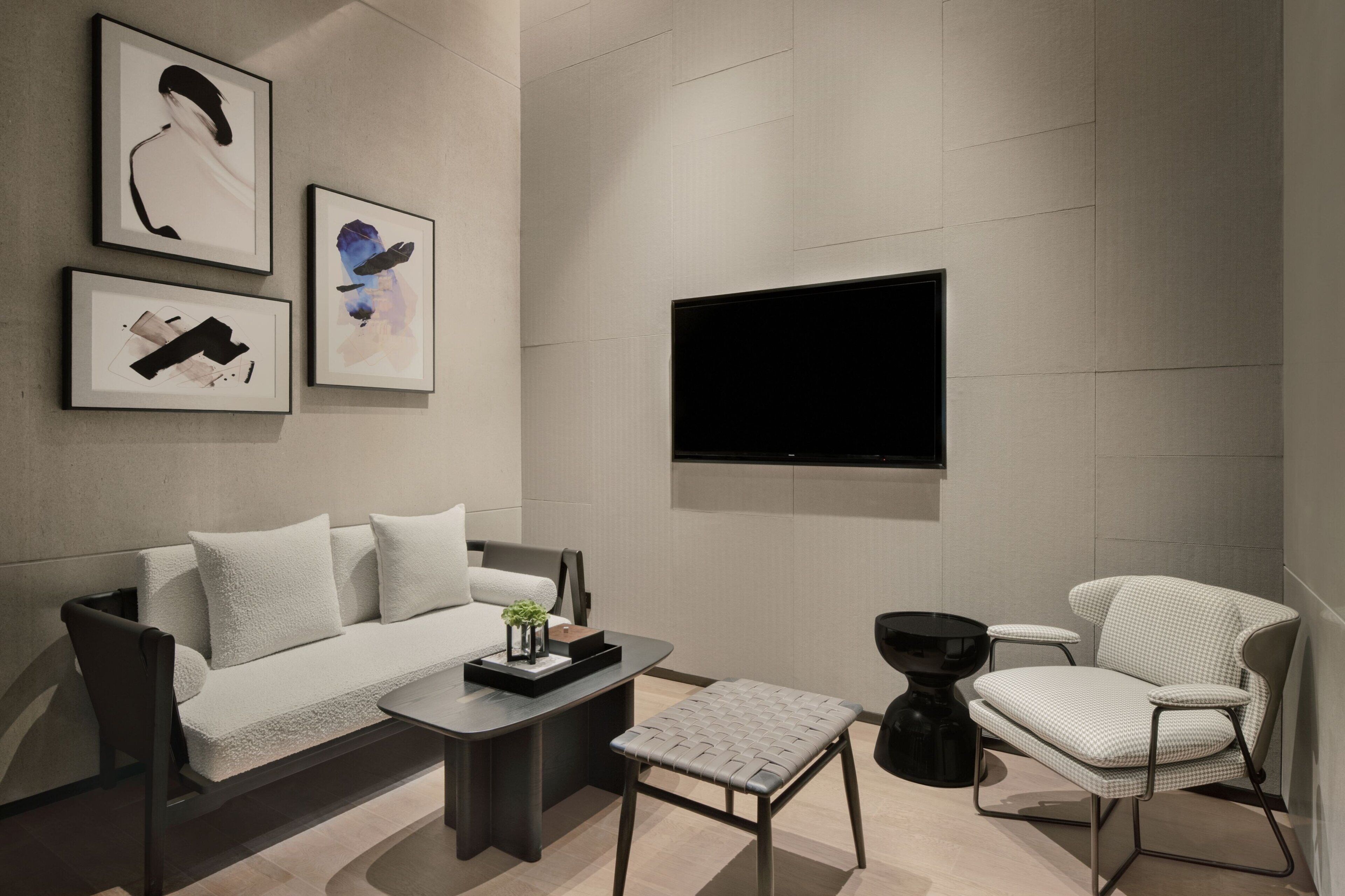 Una sala de estar moderna con un sofá, una mesa de centro, un sillón y un televisor de pantalla plana montado en la pared.
