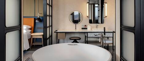 A modern bathroom with a large round sink, a mirror, and a toilet.