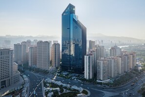 A modern high-rise building with a unique angular design, surrounded by other high-rise buildings in a cityscape. - Sheraton Lanzhou Anning (Lanzhou)