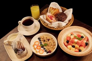 A breakfast setting with a cup of coffee, a glass of orange juice, a basket of pastries, a bowl of cereal with fruits, and a tray with a newspaper. - Sheraton Lanzhou Anning (Lanzhou)